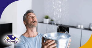 Worried man catching water from ceiling leak with a metal bucket.