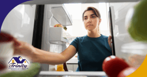 Woman looking inside a refrigerator while reaching for food.
