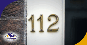 Brass house number 112 mounted on a white doorframe.