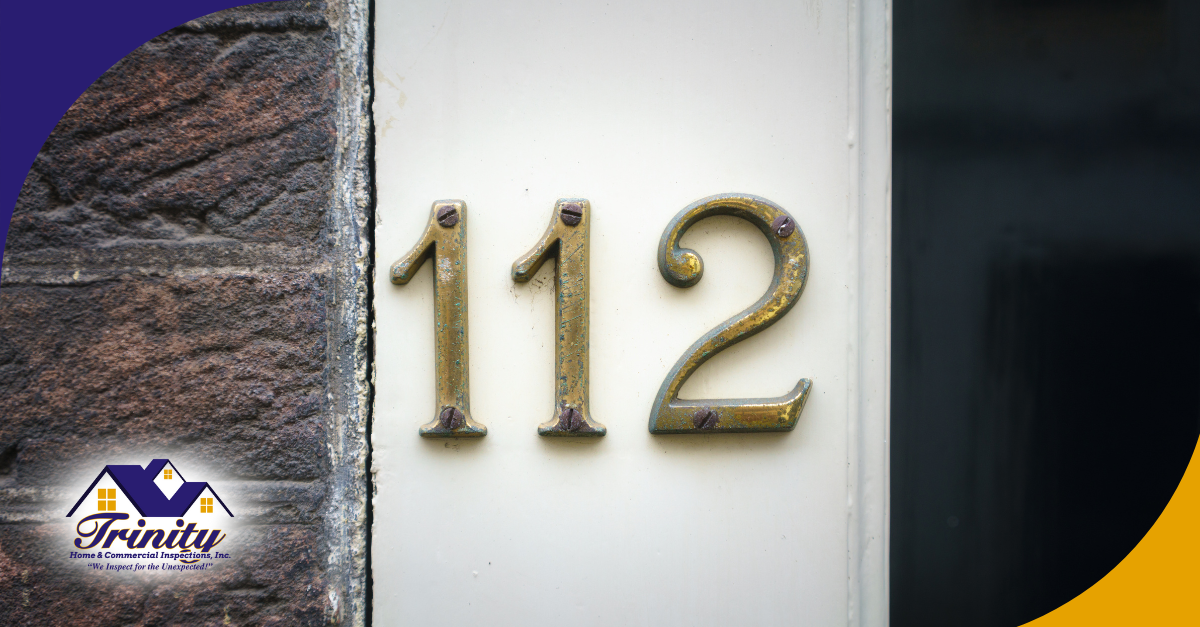 Brass house number 112 mounted on a white doorframe.