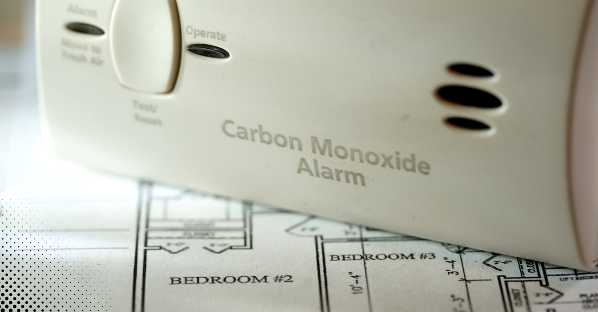 Carbon monoxide alarm resting on a floor plan of a home.